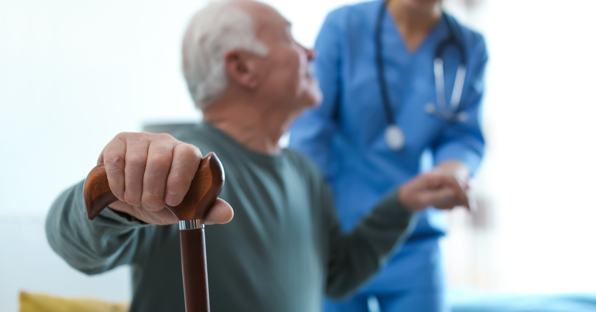 Hombre mayor utilizando un bastón mientras un profesional de la salud lo asiste, representando la atención geriátrica.